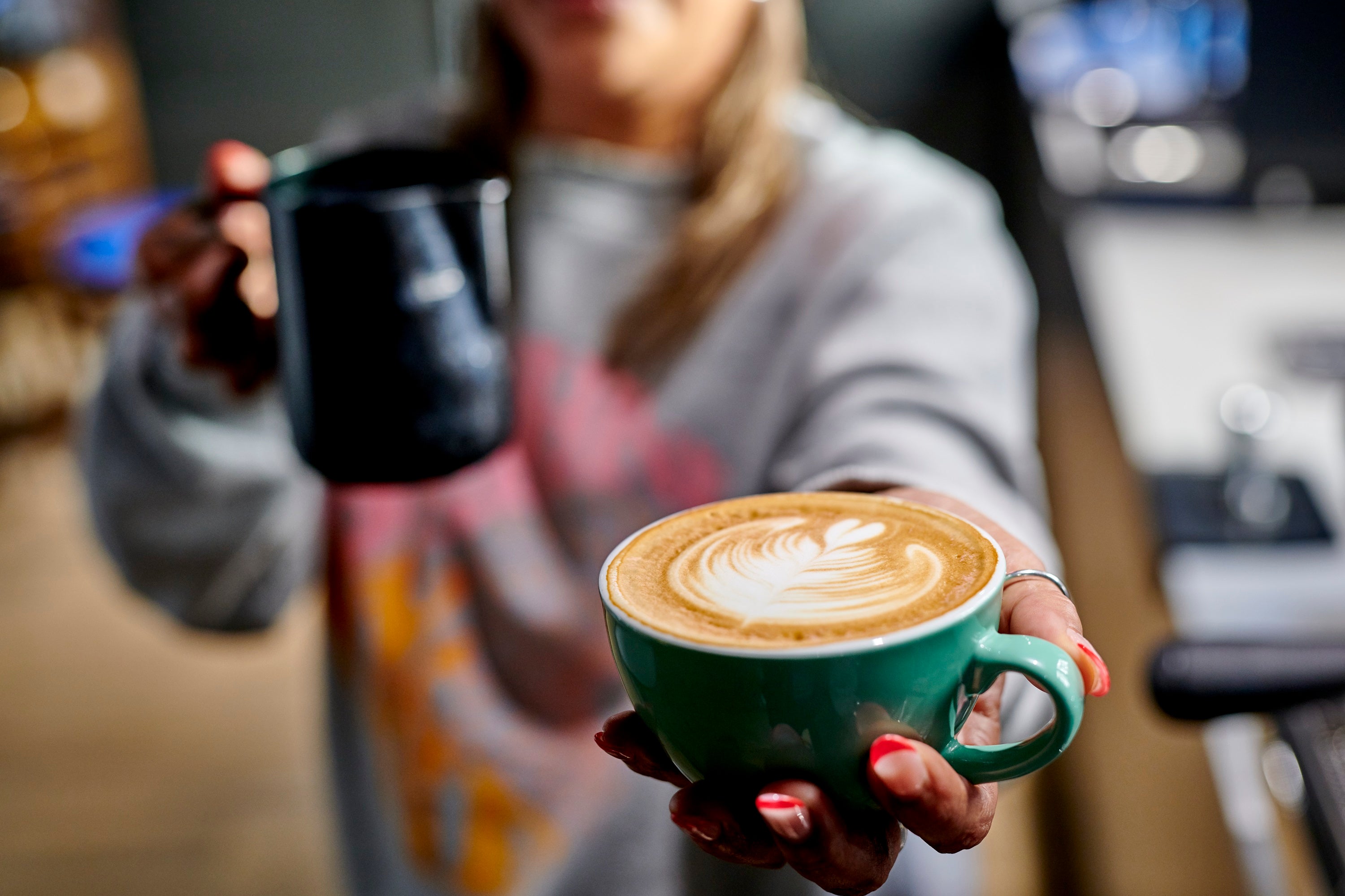 Barista school student holding a milk jug and showing off their latte art