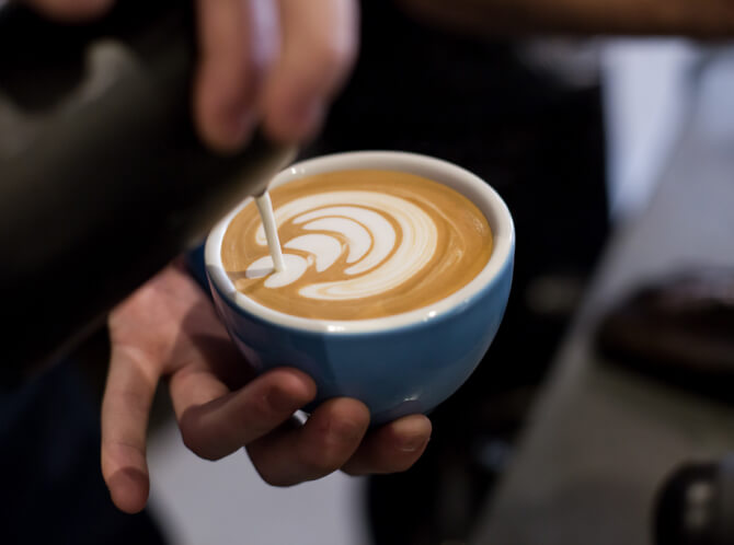 Delicate latte art being poured into cup of 200 degrees coffeecoffee