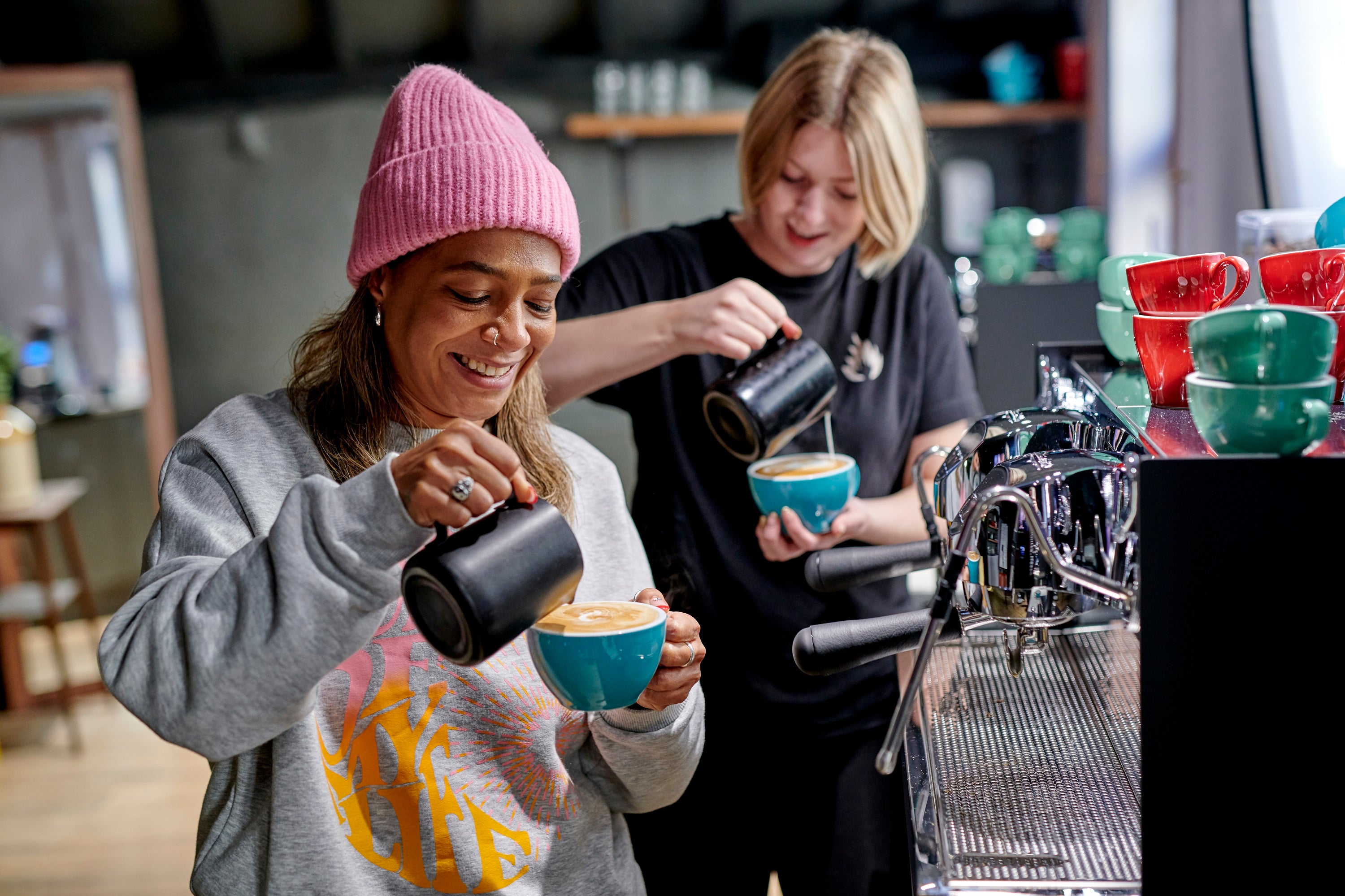 Two women doing latte art in the Intermediate Barista Course