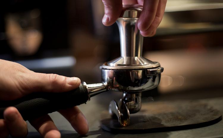 A coffee tamper being used